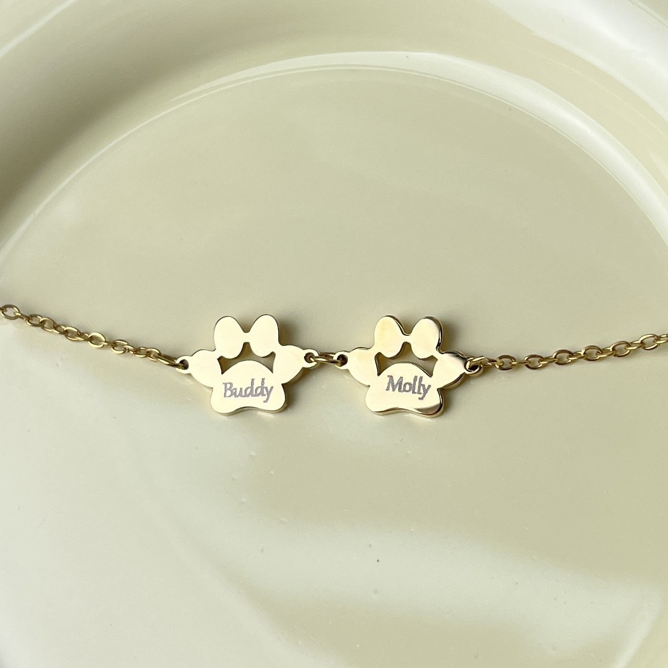 Gold pawprint charm bracelet engraved with pet names Buddy and Molly
